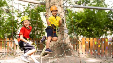 Orman macera parkında bir çocuk. Çocuklar yüksek ip izlerine tırmanıyor. Çeviklik ve çocuklar için açık hava eğlence merkezine tırmanma. Küçük kız dışarıda oynuyor. Okul bahçesinde iple oyun oynanır..