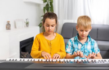 Erkek ve kız kardeş sentezleyici oynuyorlar. Çocuklar piyano çalar. aile oyunları