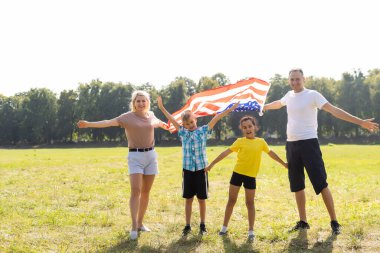 Tarlada Amerikan bayrağı taşıyan güzel bir aile. Bağımsızlık Günü, 4 Temmuz.