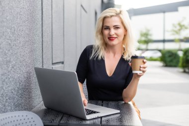 Kafedeki bilgisayarın başında çalışan genç bir iş kadını. Dizüstü bilgisayarda çalışan şekil değiştiren genç bir kız..