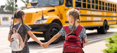 Okul servisinin yanındaki neşeli küçük kızlar. Geri çekilin. Okul konseptine dönelim..