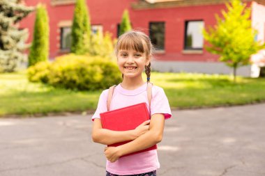 Elinde kitaplarla mutlu, gülümseyen, neşeli kız çocuğu. Yüz ifadesi olan liseli kız. Eğitim kavramı, okuma, okula dönüş..
