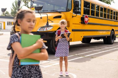 Okul servisinin yanındaki neşeli küçük kızlar. Geri çekilin. Okul konseptine dönelim..