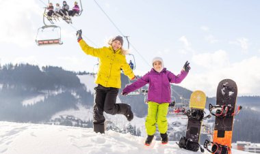Anne ve kızı kış tatilinde snowboard yapıyor.