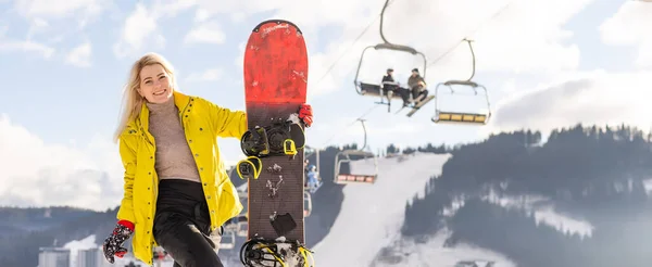 Giovane donna che tiene snowboard in località invernale — Foto Stock