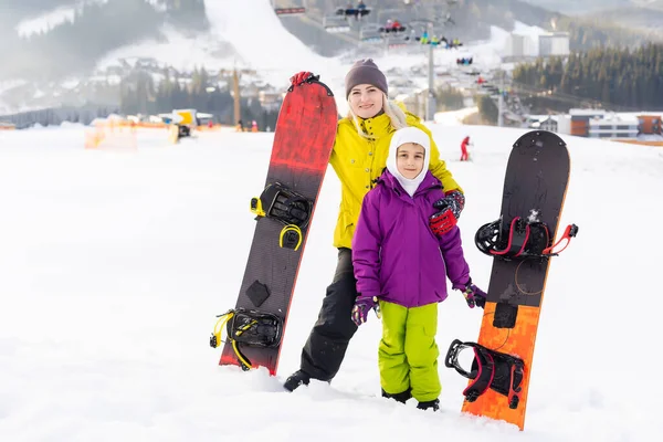 Mãe e filha com snowboards estão brincando na neve — Fotografia de Stock