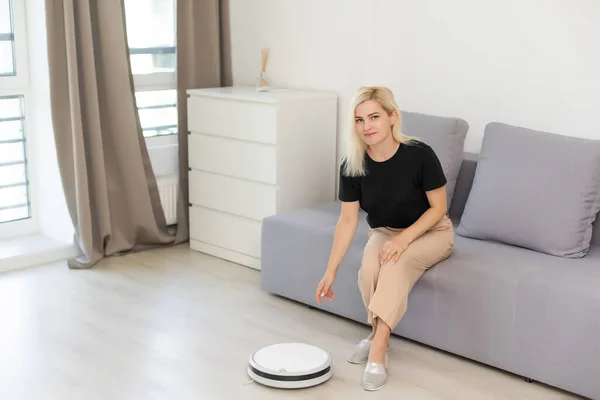 Människor, hushållsarbete och teknik koncept - lycklig kvinna med surfplatta dator och robot dammsugare hemma — Stockfoto