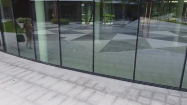 Alışveriş merkezinde elinde kağıt poşetlerle cam vitrinlere bakan mutlu kadın. Çekici, şık bir kadın. Sezonluk satışlarda kıyafetlere hayran gülümsüyor..