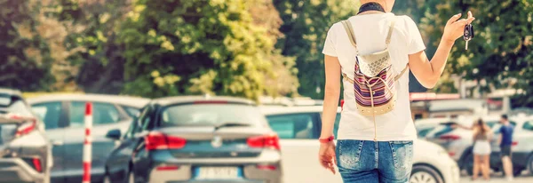 Glad kvinna fnittrar när du står utanför på stor parkeringsplats med bilar i bakgrunden. Inkluderar kopieringsutrymme. — Stockfoto