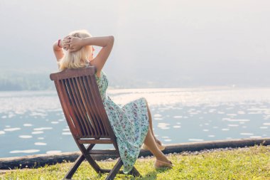 Bir güneşlenme dağlarda oturan güzel sarışın. Konsept: dağ turizm ve dağ seyahat.