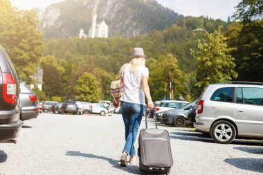 Yazın bir kadın tatile çıkıyor, doğa ve dağların arka planında bir bavulla tatile. Seyahat konsepti, dağlarda güzel bir yerde hafta sonu.