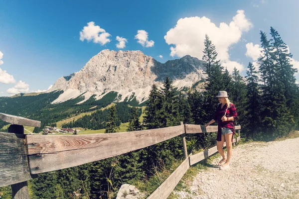 Rückansicht einer Wanderin auf einem Wanderweg in den Alpen bei Ehrwald, Tirol, Österreich. Landschaft mit Gras, Bäumen, felsigen Bergen und blauem Himmel. — Stockfoto