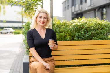 Güzel kadın ofis binası yürüyüş kahve ile çalışma olacak. İş için yolda elinde sıcak bir içecek fincan şehir sokak üzerinde tutan başarılı iş kadın portresi