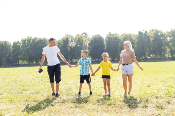 Счастливая любящая семья гуляет на свежем воздухе в свете заката. Отец, мать, сын и дочь. — стоковое фото