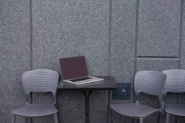 Kafedeki masada dizüstü bilgisayarla basit çalışma alanının görünümünü kapat