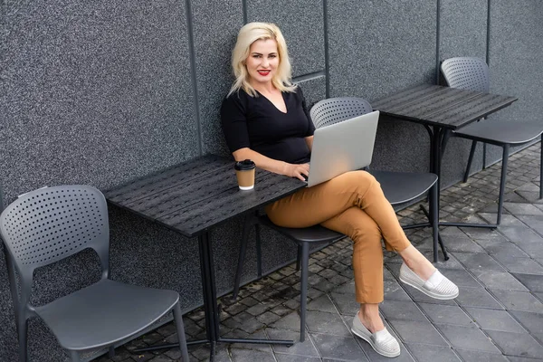 Jovem fêmea com sorriso bonito sentado com net-book portátil no interior moderno café durante o tempo de recreação, encantador estudante mulher feliz usando computador portátil para se preparar para o trabalho do curso — Fotografia de Stock