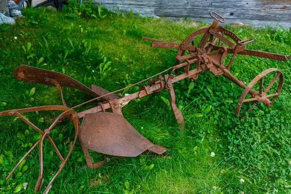 Velho arado enferrujado deitado na grama — Fotografia de Stock