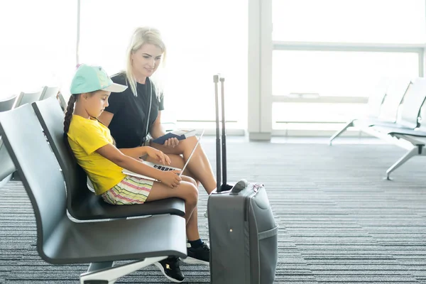 Familia en el aeropuerto. Atractiva mujer joven y linda hija pequeña están listos para viajar. Concepto de familia feliz. —  Fotos de Stock