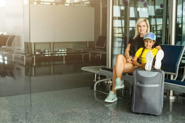 Familia en el aeropuerto. Atractiva mujer joven y linda hija pequeña están listos para viajar. Concepto de familia feliz. —  Fotos de Stock