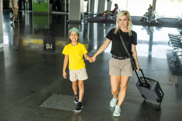 Familia en el aeropuerto. Atractiva mujer joven y linda hija pequeña están listos para viajar. Concepto de familia feliz. —  Fotos de Stock