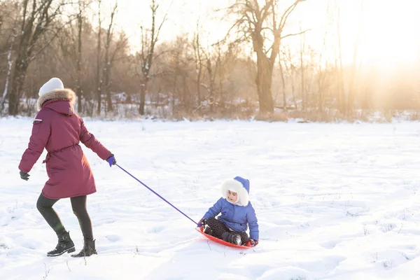 Luge à l'hiver, la mère porte sa fille sur un traîneau sur glace — Photo