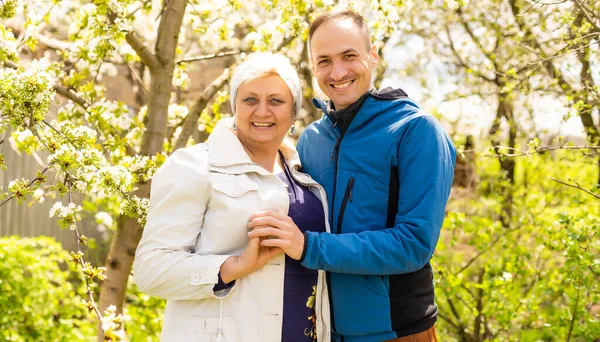 Mann umarmt seine Mutter im Garten — Stockfoto