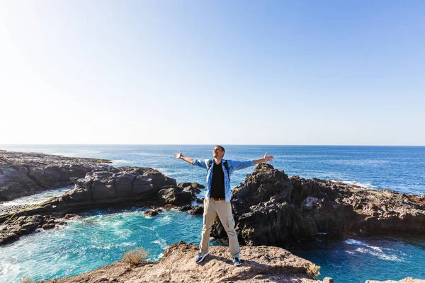 Junger heller attraktiver Mann, der am Meer steht und die Situation am Strand kontrolliert. Ozeanwellen und blauer Himmel Hintergrund — Stockfoto