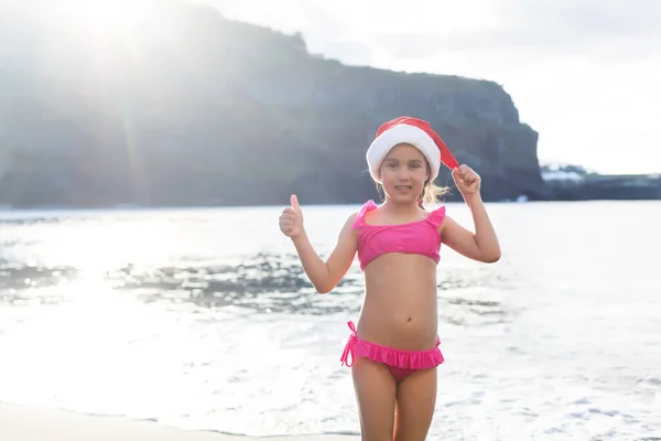 Little cute girl in red hat santa claus on the beach — Stock Photo, Image