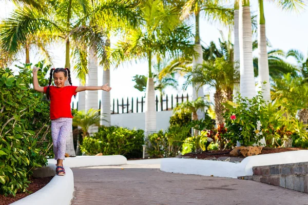 Klein meisje loopt in de buurt van palmbomen, vakantie — Stockfoto