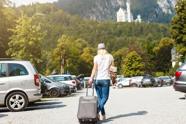 Junge Frau läuft mit Koffer auf Parkplatz der Burg Neuschweistein — Stockfoto