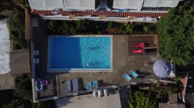 Anne ve küçük kızı havuzda eğleniyor. Annem çocukla oynuyor. Aile yüzme havuzunda yaz tatilinin tadını çıkarıyor..