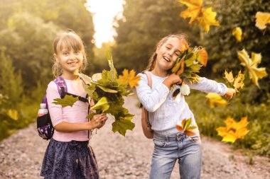 Sonbahar manzarası arasında okullu kızlar.
