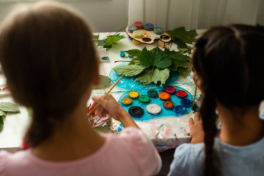 İki liseli kız yaprak çizer, kızlar sonbahar yapraklarını boyarlar