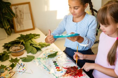 Kuru meşe yaprağını keserken, öğretmenine ders için süslemeler yaparken makaslı tatlı kız öğrenci.