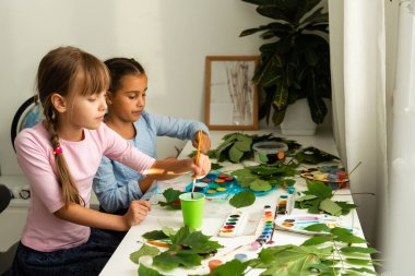 Çocuklar için sonbahar sanatı. Akçaağaç yaprağından yapılmış hayvan tilkisi. Çocuk sanatı ve yaratıcı. Doğal malzemelerden yapılmış el işi. Kızlar boyayla resim yapar..