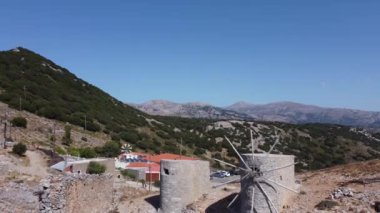 Golyazi Bursa 'daki antik yel değirmeni ve taştan yapılmış ana yapısı ve muhteşem mavi gökyüzü ve bahar zamanı yeşil ağaçlarla kaplı ahşap pervanesi.