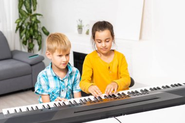 Erkek ve kız kardeş sentezleyici oynuyorlar. Çocuklar piyano çalar. aile oyunları