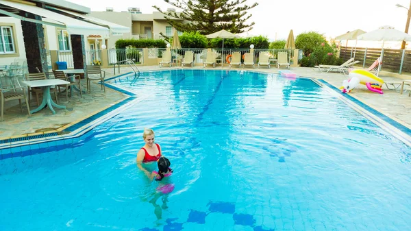 Hermosa mujer con su hija en la piscina — Foto de Stock