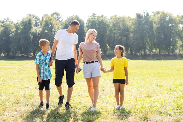 Feliz família amorosa andando ao ar livre à luz do pôr do sol. Pai, mãe, filho e filha. — Fotografia de Stock