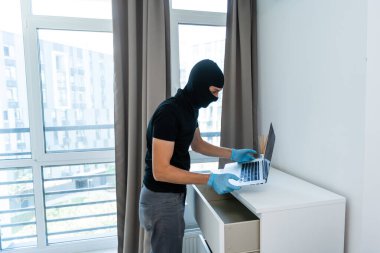 Laptop çalan siyah kar maskeli bir hırsız. Hırsız lüks bir dairede suç işledi.