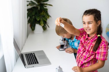 yenilenebilir enerji, çocuklar, teknoloji, bilim ve insanlar kavramı - dizüstü bilgisayarı ve mikroskop modeli olan çocuklar veya arkadaşlar