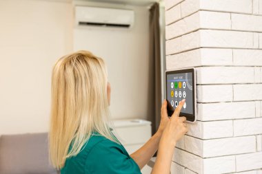 Tablette akıllı ev kontrolü. Arka planda oturma odasının içi..