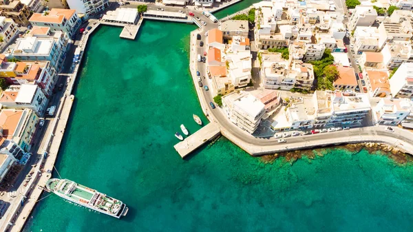 Agios Nikolaos. Kreta. Griechenland. Gebäude am Ufer des Sees Voulismeni und Boote an der Seebrücke — Stockfoto