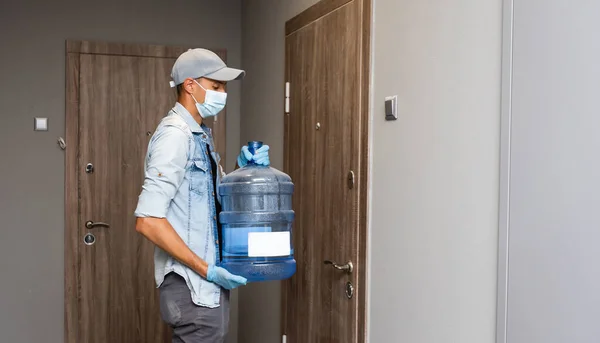 Consegna acqua uomo indossare maschera protettiva viso medico durante pandemia coronavirus — Foto Stock