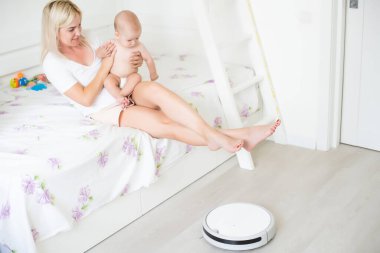 Bebeğin yanında robot süpürge var.