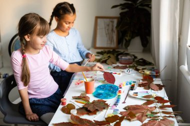 İki liseli kız yaprak çizer, kızlar sonbahar yapraklarını boyarlar