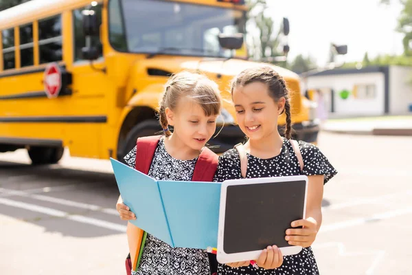 Vzdělání: Usmívající se studenti přátelé připraveni do školy vedle školního autobusu — Stock fotografie