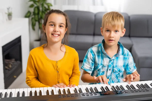 Hermano y hermana tocan el sintetizador. Los niños tocan el piano. juegos familiares — Foto de Stock