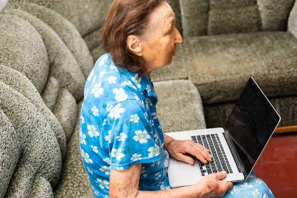 Donna anziana che guarda lo schermo di computer portatile durante videochiamata da casa — Foto Stock