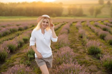 Lavanta tarlasında duran genç bir kadın ve arka planda gün doğumu.